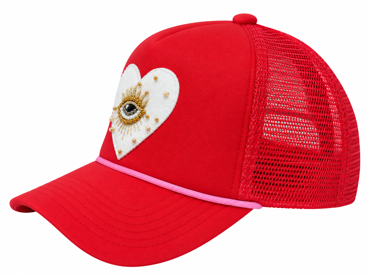 Side view of red mesh trucker hat with white beaded evil eye heart patch and pink rope trim